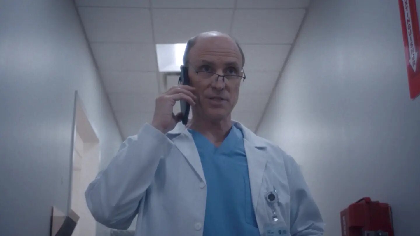 Drew Moore as Dr. Son speaking on the telephone in a hospital hallway