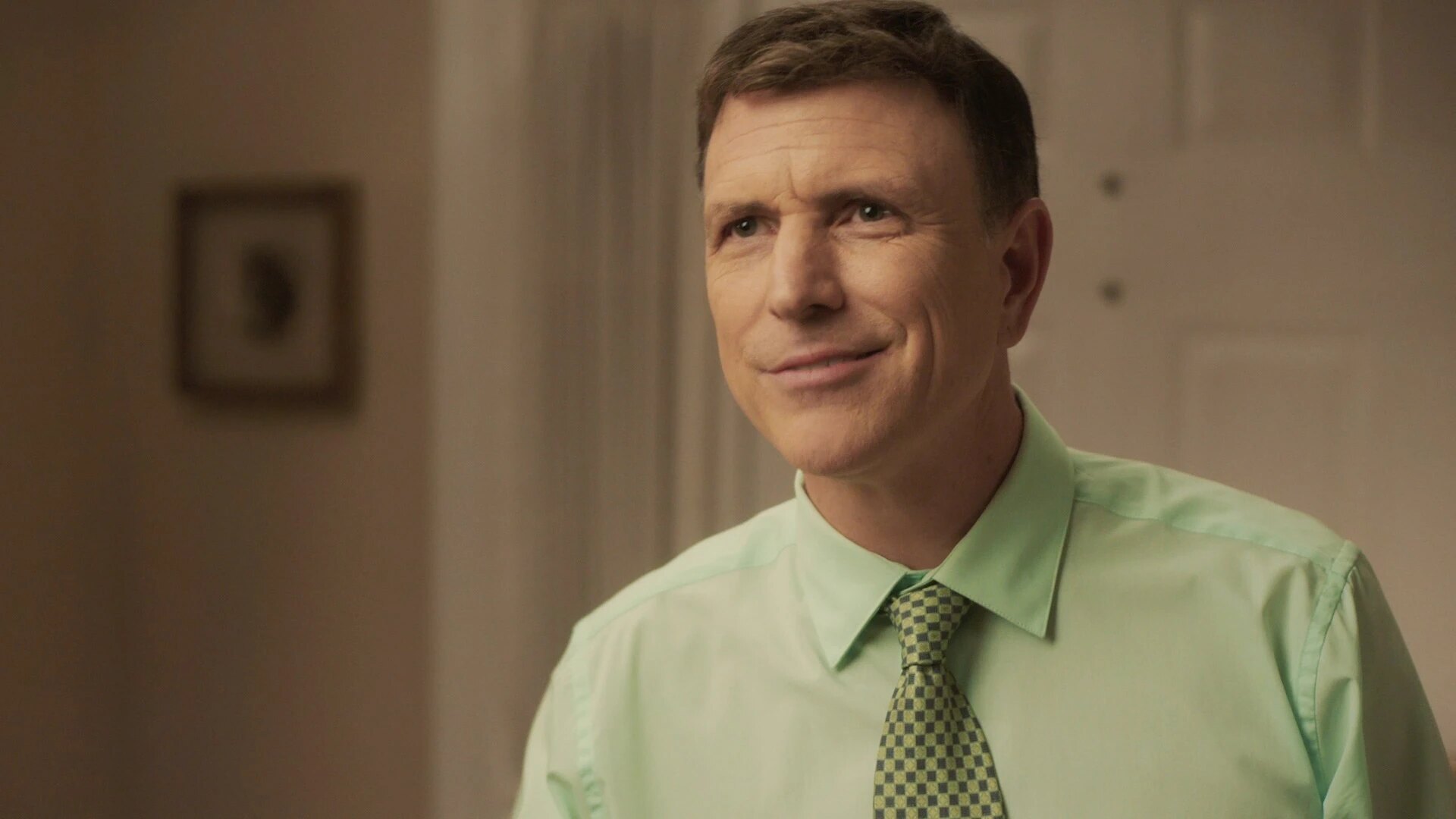 Drew Moore as Richard Dobbs in a light green shirt and patterned tie